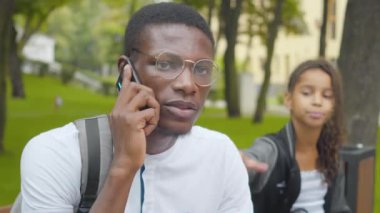 Afrika kökenli Amerikalı bir adamın telefondaki görüntüsü onun dikkatini çekmeye çalışan sıkılmış küçük bir kız gibi. Sunny Park 'ta ablasını görmezden gelen meşgul bir ağabey. Meşguliyet ve eğlence çatışması.