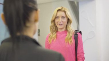 Genç sarışın, kahverengi gözlü bir kadının portresi arkadaşlarıyla konuşuyor ve gülüyor. Slim Kafkasyalı sporcu kadın antrenmandan sonra spor salonunda esmer kadınla sohbet ediyor..