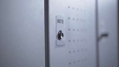 Erkek eli bilezik anahtarıyla açtığı soyunma odasındaki dolabın yakın çekimi. Spor kulübündeki anahtarsız sistem. Tanımlanamayan sporcu içeride değişiyor..