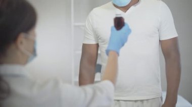 Beyaz kadın doktor tanınmayan Afrikalı Amerikalı hastaya ilaç veriyor. Genç esmer kadın Covid-19 'daki adamı tedavi ediyor. Koronavirüs karantinası için tıbbi randevu.