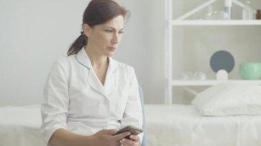 Çaresiz Kafkasyalı kadın telefonla arıyor ve gidiyor. Covid-19 salgınında ailesi için zamanı olmayan depresif kadın doktor portresi. Coronavirus sırasında sağlık çalışanlarının sorunları.