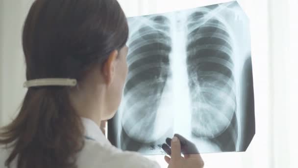 肺X線を調べる白人医師。病院のラジオグラフを見て深刻な専門家の肩の上に撮影。Covid-19ウイルス呼吸器感染症の合併症.コロナウイルスの発生. — ストック動画