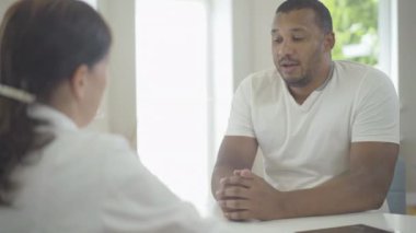 Ciddi Afrika kökenli Amerikalı bir adam hastanede beyaz bir kadınla el sıkışıyor. Hastanedeki bir hastanın portresi. Klinikteki kadın hekim danışmanı.