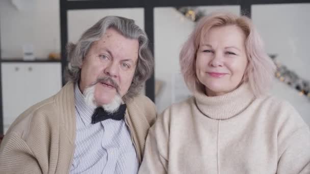 Retrato de hombre mayor guapo y hermosa mujer madura posando en casa en la víspera de Año Nuevo. Feliz pareja caucásica relajada mirando a la cámara y sonriendo. Feliz jubilación. Concepto de Navidad. — Vídeos de Stock