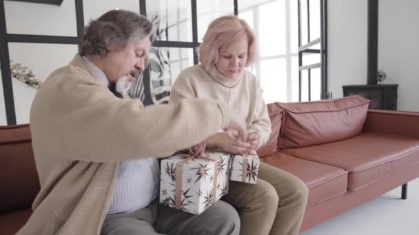 Starszy biały mężczyzna i kobieta pakujący prezenty świąteczne w domu. Portret pozytywnych emerytów płci męskiej i żeńskiej przygotowujących się do Nowego Roku. Koncepcja sezonu wakacyjnego. — Wideo stockowe