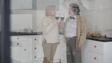 Noel arifesinde kadehlerini kırmızı şarapla tokuşturan üst düzey beyaz bir çift. Mutlu olgun bir adamla kadının yeni yılı birlikte geçirdiği camın arkasında çekim yapmak. Aşk ve bağlanma kavramı.