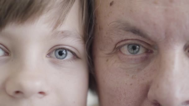 Büyükbabanın ve torununun kameraya aşırı yakın çekimleri. Kafkasyalı yaşlı bir adamın portresi ve gri gözlü küçük bir çocuk.. — Stok video