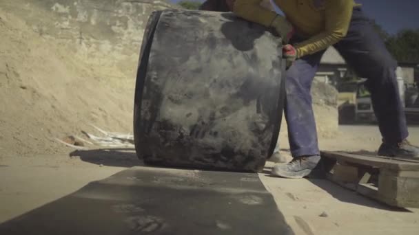 Vista frontal de la cinta transportadora con fuertes trabajadores de fábrica rodando banda de goma bajo la luz del sol al aire libre. Manual de trabajo duro empleados caucásicos que trabajan en la fábrica. — Vídeo de stock