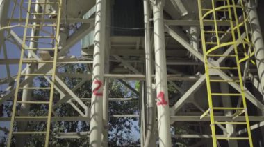 Kamera devasa bir çelik beton depolama silosu boyunca hareket ediyor. Güneşli yaz gününde beton için inşaat ya da depo. İnşaat malzemeleri üretim alanı.