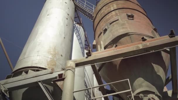 Enorma industriella reservoartorn i bakgrunden av klarblå himmel utomhus. Bred bild av cement lagring silor på betong fabrik. Kameran rör sig runt konstruktioner. — Stockvideo