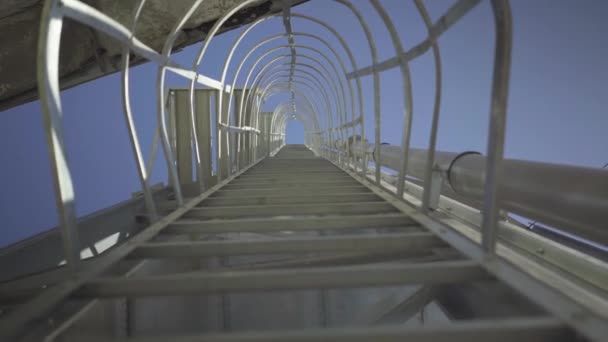 Botten vy över stora stegen på cement lagring silo med klarblå sommar himmel i bakgrunden. Enorm behållare av rostfritt stål på produktionsanläggning för betong. — Stockvideo