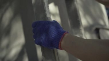 Kamera, beyaz eldivenli erkekleri takip ediyor. Profesyonel fabrika işçisi, güneşli yaz gününde üretim alanında merdivenleri tırmanıyor..