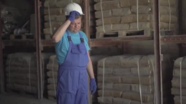 Beyaz kaskı ayarlayan ve fabrika deposunu terk eden profesyonel bir çalışanın portresi. Fabrika deposunda kendine güvenen Kafkas işçisi.