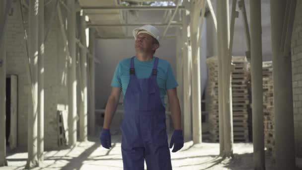 Muž běloch kontroluje staveniště venku. Portrét sebevědomého profesionála kráčejícího po staveništi a vzhlížejícího. Foreman kontroluje objekt. — Stock video