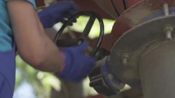 Close-up de mãos masculinas em luvas de trabalho girando roda em equipamentos industriais ao ar livre. Trabalhador de fábrica irreconhecível ajustando transportador de parafuso de cimento no local de produção de concreto. — Vídeo de Stock