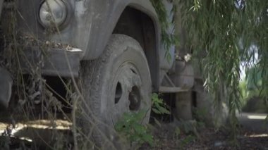 Kırık endüstriyel kamyonun tekerleği fabrikanın enkazına yakın çekim. Fabrika harabelerinde terk edilmiş paslı nakliye aracı..