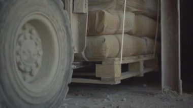 Depoda paketlenmiş materyalleri depolayan yükleyicilere yakın çekim. Endüstriyel makineler depoda imalat için malzemeleri boşaltıyorlar..