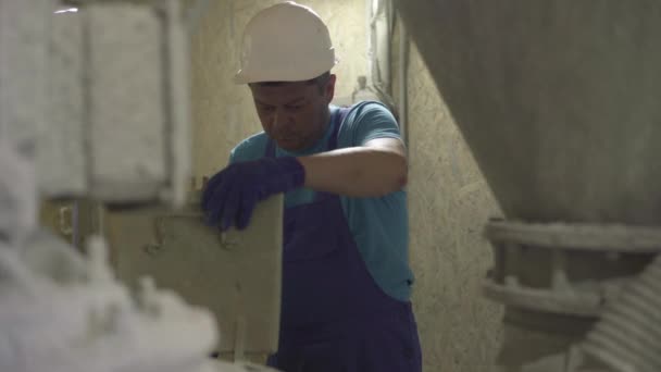 Tiro médio do trabalhador masculino caucasiano sério que controla o equipamento na fábrica de produção de cimento. Processo de controle visual da unidade de mistura de concreto. Homem profissional no local de trabalho na fábrica. — Vídeo de Stock