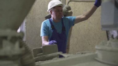 Fabrikada güvenlik kaskı açan ve çekiç kullanan profesyonel bir adam. Üniformalı beyaz adamın portresi fabrikada çimento karıştırma ünitesini tamir ediyor..