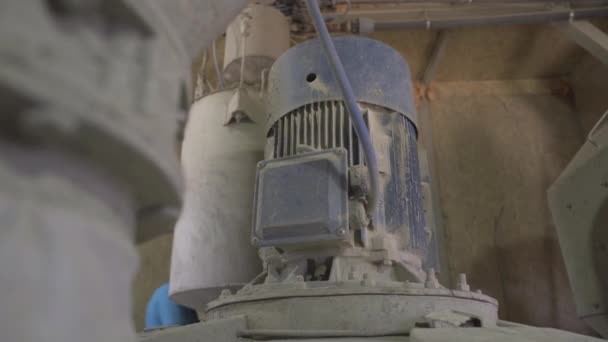 Motor en la máquina mezcladora de concreto con trabajador de fábrica en casco de seguridad que pasa en el fondo. Enormes equipos industriales en el sitio de producción. — Vídeos de Stock