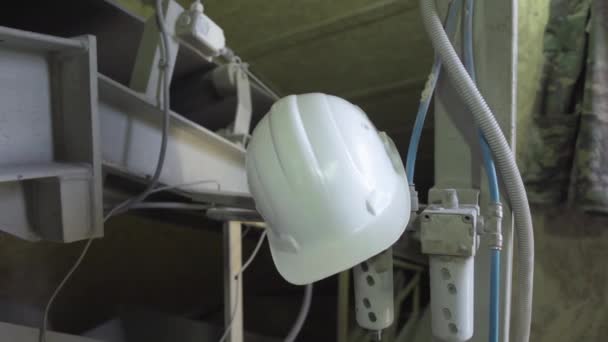 Белый защитный шлем висит на стальных конструкциях на производственной площадке. Средство индивидуальной защиты на заводе или фабрике в помещении. — стоковое видео