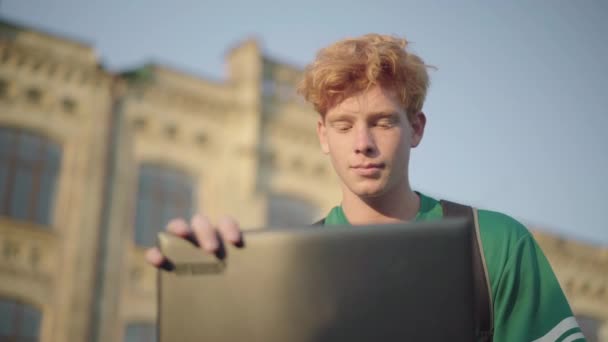 Ritratto di sicuro studente intelligente rossa al tramonto all'aperto. Giovane caucasico bell'uomo che chiude il portatile, sospira e distoglie lo sguardo al tramonto. — Video Stock