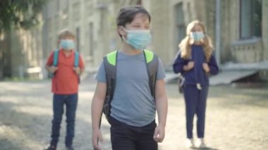 Yüzü maskeli ortaokul öğrencileri güneşli bir günde okul bahçesinde eğleniyorlar. Kafkas öğrencilerinin rahatlamış portresi. Covid-19 salgınını inceledikten sonra çocukların keyfi yerinde..