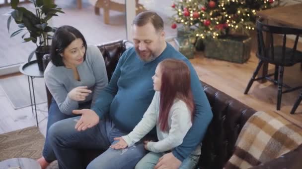 Beyaz bir kadın ve kızın neşeli orta yaşlı bir adama beşlik çakmasının olumlu açılı görüntüsü. Mutlu beyaz aile portresi evde yeni yılın tadını çıkarıyor. Noel kutlaması. — Stok video