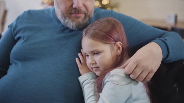 Side view close-up van charmante blanke meisje praten met onherkenbare man op oudejaarsavond thuis. Portret van zorgeloze dochter genieten van Kerstmis weekend met vader binnen. — Stockvideo