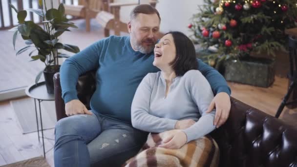 Fröhliches kaukasisches Liebespaar, das an Heiligabend zu Hause scherzt und lacht. Porträt: Unbekümmert entspannte Männer und Frauen, die sich an Silvester im Haus amüsieren. — Stockvideo