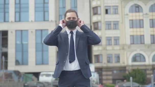 Přední pohled na spokojeného bělošského podnikatele, jak odhazuje masku Covid-19 a usmívá se. Kamera se blíží k šťastnému mladému muži oslavujícímu konec koronavirové pandemické karantény. — Stock video