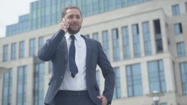 Mutlu beyaz adam telefonu kapatıyor ve zafer jesti yapıyor. Başarılı iş anlaşmasının heyecanlı genç işadamının portresi. Şehir dışında eğlenen yakışıklı bir girişimci..