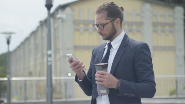 认真自信的商人在户外用智能手机上网的侧视图。凝重的白人男子在眼镜中的画像，以检查最新的股票新闻. — 图库视频影像