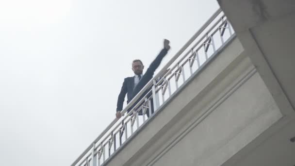 Hombre caucásico suicida en traje formal y anteojos trepando por la cerca del puente. Vista inferior amplia toma de empresario deprimido tratando de suicidarse en la ciudad urbana. — Vídeo de stock