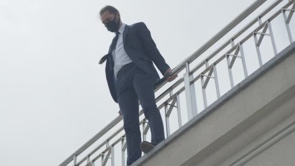 Portrait of desperate young businessman in Covid-19 face mask standing on city bridge edge ready to jump. Wide shot of frustrated Caucasian man lost his business during coronavirus lockdown. — Stock Video