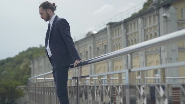 Vista lateral amplia toma de desesperado hombre de negocios caucásico en traje de pie en el borde del puente tratando de saltar hacia abajo. Joven frustrado deprimido listo para suicidarse. — Vídeos de Stock