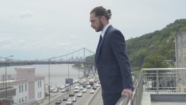 Vista lateral de suicida hombre de negocios caucásico de pie en la valla del puente con los coches a lo largo de la carretera hacia abajo. Retrato de plano medio del joven frustrado deprimido que intenta suicidarse. — Vídeos de Stock