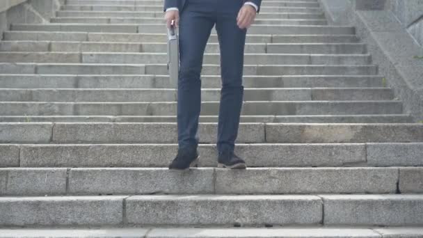 Exhausted Caucasian businessman walking down the stairs and sitting down. Wide shot portrait of tired young man in eyeglasses resting in urban city outdoors. Business stress concept. — Stock Video