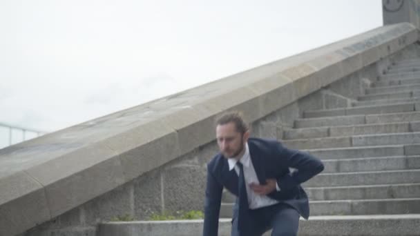 Young overworked businessman walking down stairs and having heart attack. Camera approaches to ill Caucasian man with heart failure because of overworking. Health care concept. — Stock Video