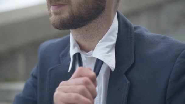 Unrecognizable exhausted businessman loosing necktie and sighing. Tired young Caucasian bearded man sitting on city stairs outdoors and thinking. — Stock Video