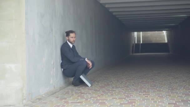 Gros plan d'un homme déprimé en costume assis contre le mur dans un passage souterrain. Frustré stressé surmené homme d'affaires caucasien penser. Concept de fatigue et d'épuisement. — Video