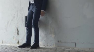 Covid-19 yüz maskeli depresif bir adam şehrin yeraltı geçidinde oturuyor. Kafkasyalı genç işadamının portresi koronavirüs salgınında işini kaybetti..
