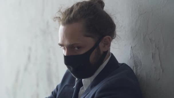 Close-up face of depressed Caucasian man in Covid-19 face mask leaning against the wall in abandoned urban underground crossing. Portrait of frustrated young businessman lost his job. Depression. — Stock Video