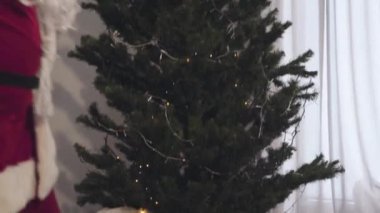 Yeni yıl ağacı boyunca kameralar hareket ediyor, Noel arifesinde iki sürpriz Noel Baba buluşması. Kırmızı kostümlü birbirine bakan kafası karışmış adamların yan görünüm portresi..
