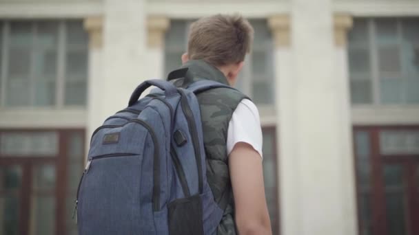 Rückenansicht eines aufgebrachten Schuljungen, der vor der Schule steht und kopfschüttelnd Nein sagt. Trauriger kaukasischer Junge, der nicht lernen will. Bildung und Intelligenz. — Stockvideo
