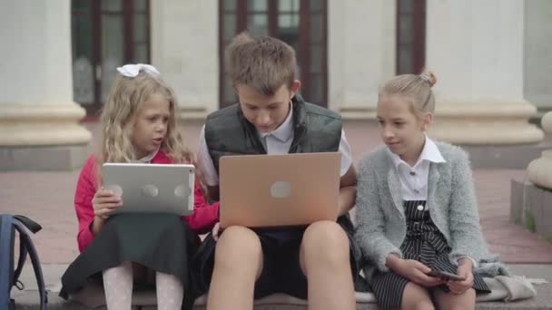 Generatie Z kinderen surfen op internet via tablet, laptop en smartphone. Portret van intelligente positieve blanke schoolkinderen die genieten van virtuele realiteit. Apparaatverslaving. — Stockvideo