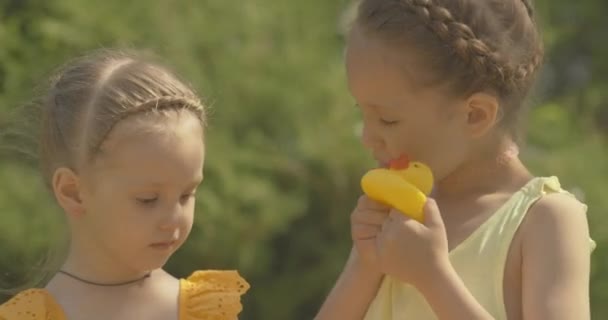 Detailní záběr hezkých holčiček, které si venku hrají s hračkami na kachničky. Portrét půvabných bělošských dětí, které si užívají slunečného dne. Dětský volný čas. Cinema 4k ProRes HQ. — Stock video