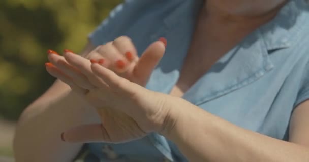 Oigenkännlig äldre kvinna som använder solkräm utomhus. Kvinnliga vita händer gnugga fuktighetskräm i armar hud. Begreppet skönhet och kosmetika. Bio 4k ProRes HQ. — Stockvideo