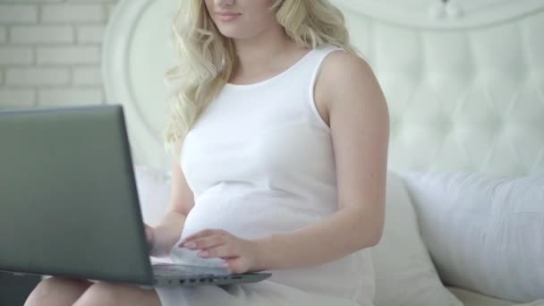 Mujer embarazada irreconocible escribiendo en el teclado del ordenador portátil y sonriendo. blogger caucásico usando las redes sociales durante el embarazo. Señora segura de comprar en línea. Tecnologías modernas y estilo de vida. — Vídeo de stock