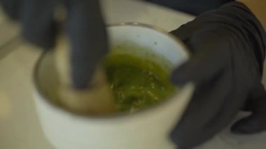 Barmen ellerinin bardakta kibrit yeşil çayı karıştırdığı yakın plan. Kafede ya da restoranda sıcak ve sağlıklı bir içecek hazırlayan tanınmamış profesyonel bir barmen..